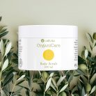 CaliVita OrganiCare Body Scrub 200 ml u bijeloj posudici s žutim krugom okružen svježim maslinovim grančicama na prirodnoj pozadini