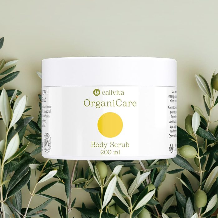 CaliVita OrganiCare Body Scrub 200 ml u bijeloj posudici s žutim krugom okružen svježim maslinovim grančicama na prirodnoj pozadini