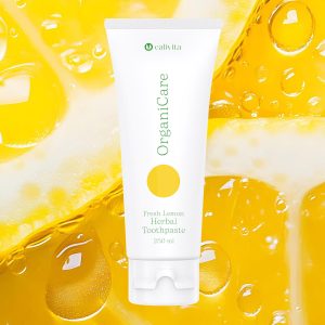CaliVita OrganiCare Herbal Toothpaste 250 ml na žutoj pozadini s limunovima i vodenim kapljicama - organska biljna pasta za zube